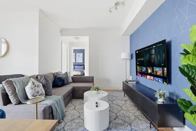 a living room with a couch and a flat screen tv at Stylish 3br Condo - Parking - 65 TV in Mississauga