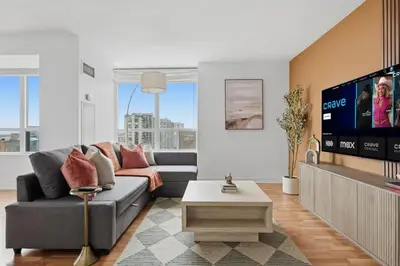 a living room with a couch and a flat screen tv at Elegant 2BR Sky Condo for 9 - Terrace - Lake Views in Mississauga