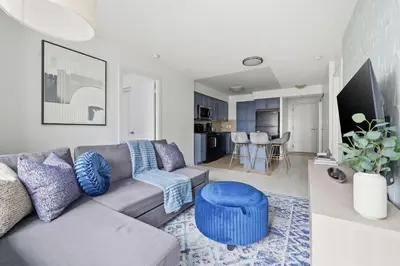 a living room with a couch and a blue stool at Designer 2BR - King Suite - Rare 2 Parking - YYZ in Mississauga