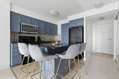 a kitchen with blue cabinets and white bar stools at Designer 2BR - King Suite - Rare 2 Parking - YYZ in Mississauga