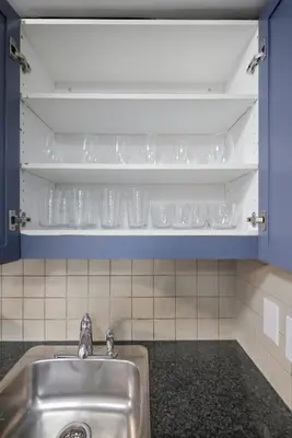 a kitchen with a sink and shelves with glasses at Designer 2BR - King Suite - Rare 2 Parking - YYZ in Mississauga