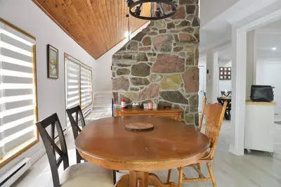 a dining room with a wooden table and a stone wall at Modern 4BR Lake Escape with Patio & BBQ Area in Kawartha Lakes