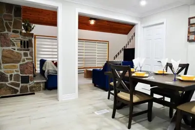 a dining room and living room with a stone fireplace at Modern 4BR Lake Escape with Patio & BBQ Area in Kawartha Lakes