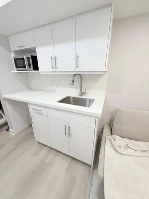 a white kitchen with a sink and a couch at Studio Basement Suite with Sofa Bed and kitchen, Entrance from Garage -Sleeps 2 in Milton