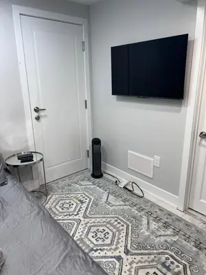 a bedroom with a bed and a flat screen tv on the wall at Studio Basement Suite with Sofa Bed and kitchen, Entrance from Garage -Sleeps 2 in Milton