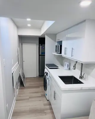 a white kitchen with a sink and a dishwasher at Studio Basement Suite with Sofa Bed and kitchen, Entrance from Garage -Sleeps 2 in Milton