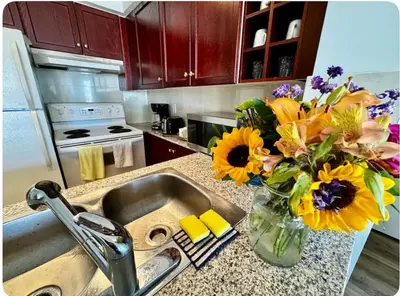 a kitchen counter with a sink with a vase of flowers at The Vicky - Centre of Attention - Location Design in Toronto