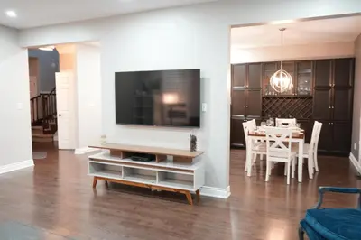 a living room with a tv and a table with chairs at Luxury 5BR Home with Spa Bath in Burlington