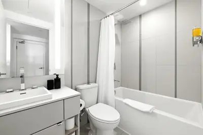 a white bathroom with a toilet and a sink at Chic Downtown Retreat with Private Patio in Toronto
