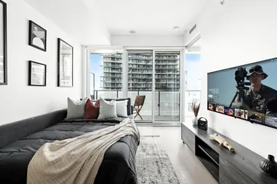 a bedroom with a bed and a flat screen tv at Chic Downtown Retreat with Private Patio in Toronto