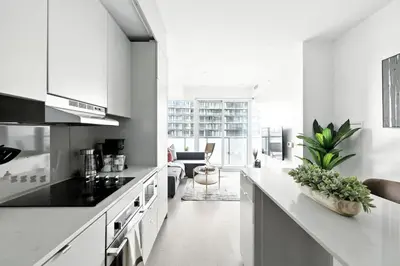 a kitchen with white appliances and a living room at Chic Downtown Retreat with Private Patio in Toronto
