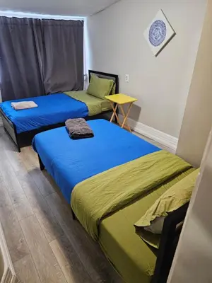 a room with two beds and a table at Superb Guest House In Downtown-Self Checkin& Fast Wifi in Toronto