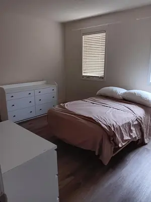 a bedroom with a bed and a dresser and a window at House near Toronto Pearson Airport in Brampton