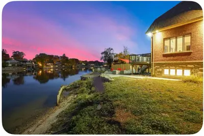 a building next to a river with a sunset at Riverside Dreams in Wasaga Beach