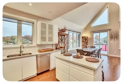 a kitchen with white cabinets and a table with chairs at Riverside Dreams in Wasaga Beach