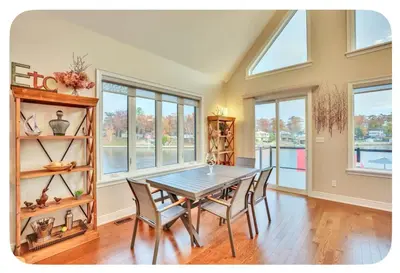 a dining room with a table and chairs and windows at Riverside Dreams in Wasaga Beach
