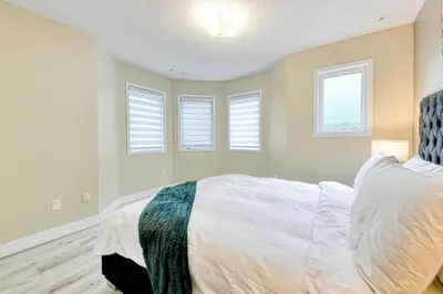 a bedroom with a bed and three windows at The Urban Family Pad in Toronto