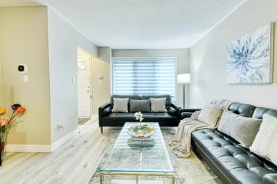 a living room with a black leather couch at The Urban Family Pad in Toronto