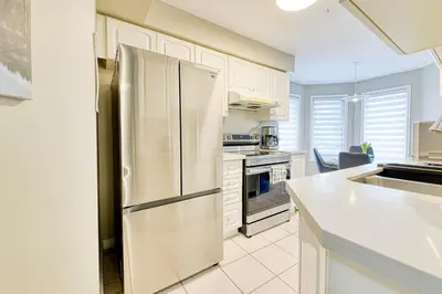 a kitchen with a stainless steel refrigerator and white cabinets at The Urban Family Pad in Toronto