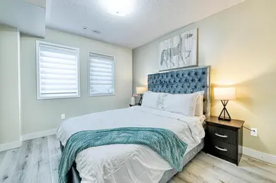 a bedroom with a large bed and two windows at The Urban Family Pad in Toronto