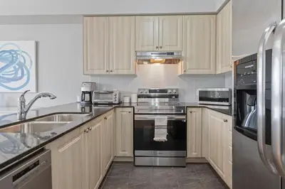 a kitchen with white cabinets and stainless steel appliances at Spacious Toronto Home Near High Park and Yorkdale Mall in Toronto