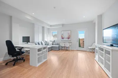 a white living room with a desk and a tv at Spacious Toronto Home Near High Park and Yorkdale Mall in Toronto