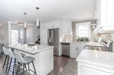a kitchen with white cabinets and a island with bar stools at Beautiful 3 bed 2 bathroom home Toronto in Toronto