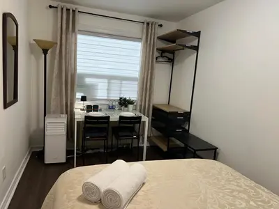 a bedroom with a bed and a table and a window at Private Room with Shared Bathroom in West-Toronto in Toronto