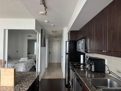 a kitchen with a sink and a room with a bed at 1 bedroom condo by lakeshore in Toronto