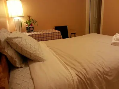 a bedroom with a white bed with a table and a lamp at Maria's Homestay in Thornhill
