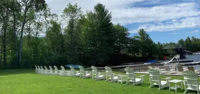 a row of white chairs sitting on the grass at #90 Lakefront 3-bdrm Chalet in Muskoka in Port Carling