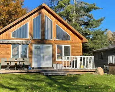 a log cabin with a porch and a table at #90 Lakefront 3-bdrm Chalet in Muskoka in Port Carling
