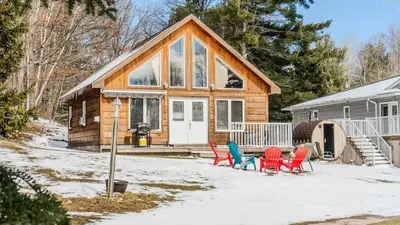 a house with red and blue chairs in front of it at #90 Lakefront 3-bdrm Chalet in Muskoka in Port Carling