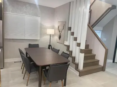 a dining room with a table and chairs and a staircase at Navigate Stays Canada Luxury Hot Tub Retreat Home in Richmond Hill