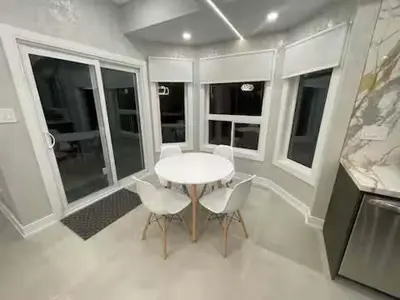 a white table and chairs in a room with windows at Navigate Stays Canada Luxury Hot Tub Retreat Home in Richmond Hill