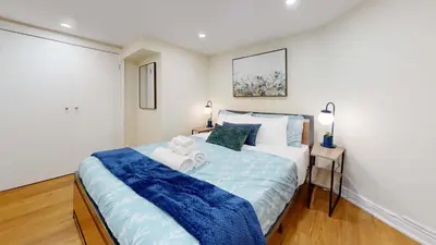 a bedroom with a large bed with a blue blanket at Cozy Basement Apartment for 4 - Near Cafes & Parks in Toronto