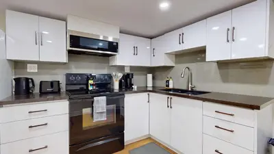 a kitchen with white cabinets and black appliances at Cozy Basement Apartment for 4 - Near Cafes & Parks in Toronto