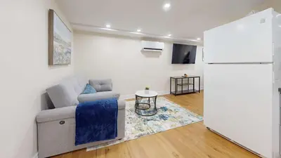 a living room with a couch and a refrigerator at Cozy Basement Apartment for 4 - Near Cafes & Parks in Toronto