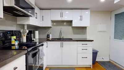 a kitchen with white cabinets and a sink at Cozy Basement Apartment for 4 - Near Cafes & Parks in Toronto