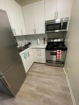 a kitchen with white cabinets and a stainless steel refrigerator at DOWNTOWN STAY-Free Wifi&Self Checkin in Toronto
