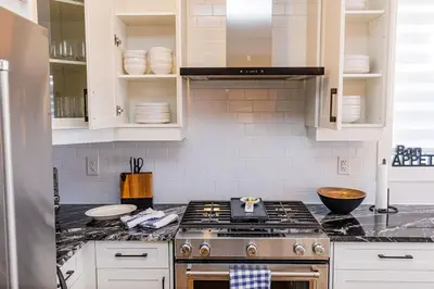 a kitchen with a stove and white cabinets at Sauna, Hot Tub & Heated Pool Blue Mountain Getaway in Blue Mountains