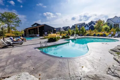 a pool at a resort with people sitting in chairs around it at Sauna, Hot Tub & Heated Pool Blue Mountain Getaway in Blue Mountains