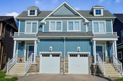a blue house with white garage doors and stairs at Sauna, Hot Tub & Heated Pool Blue Mountain Getaway in Blue Mountains