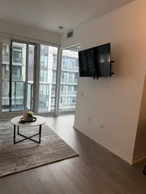 a living room with a table and a tv on the wall at Luxury Condo Downtown Toronto in Toronto