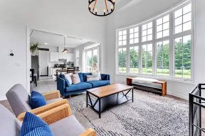 a living room with blue couches and a table at Spacious & New Prince Edward County Villa in Carrying Place