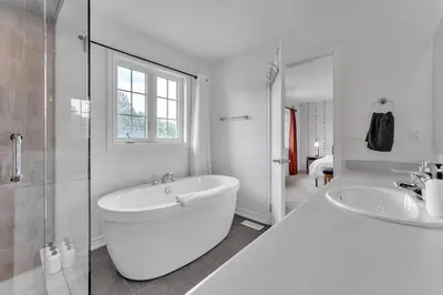 a white bathroom with a tub and two sinks at Spacious & New Prince Edward County Villa in Carrying Place
