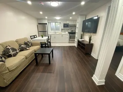 a living room with a couch and a table and a kitchen at Adorable private 2 bedroom basement unit in Toronto