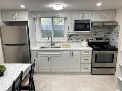 a kitchen with white cabinets and stainless steel appliances at Adorable private 2 bedroom basement unit in Toronto