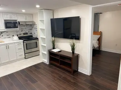 a kitchen with a large flat screen tv on a wall at Adorable private 2 bedroom basement unit in Toronto