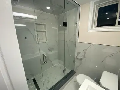 a bathroom with a glass shower with a toilet at Adorable private 2 bedroom basement unit in Toronto